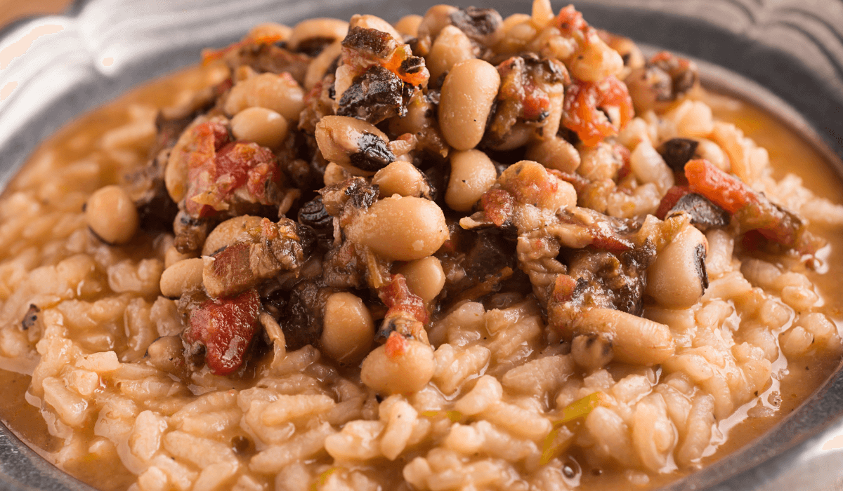 A plate of black eyed peas risotto topped with beans and tomatoes.