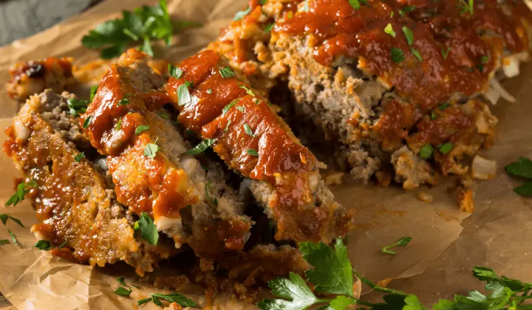 Smoked meatloaf with savory sauce and fresh parsley, served on a rustic brown paper.