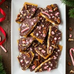 Bowl of homemade Christmas crack candy topped with chocolate and nuts